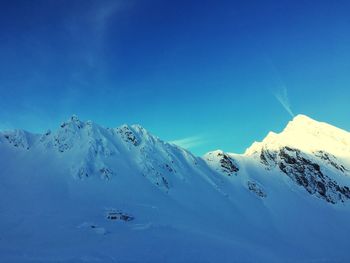 Scenic view of snowcapped mountains against blue sky