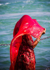 Close-up of woman with red umbrella standing in sea