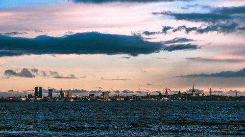 Scenic view of sea and buildings against sky during sunset