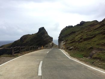 Country road against cloudy sky