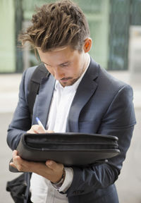 Businessman writing on folder outdoors
