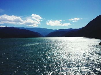 Scenic view of sea and mountains against blue sky