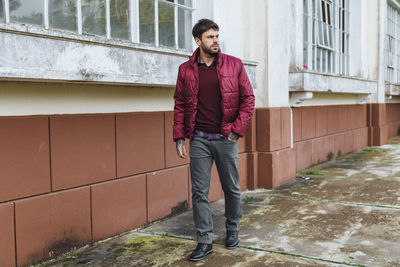 Full length portrait of young man standing against wall