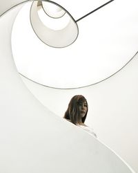 Low angle view of thoughtful young woman standing at spiral staircase