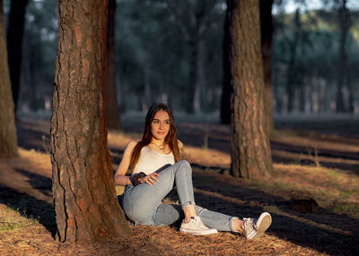 Woman sitting on tree trunk