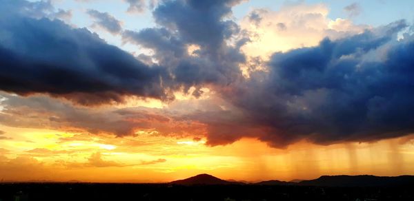 Silhouette landscape against dramatic sky during sunset