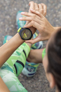 From above of crop anonymous female runner checking pulse on modern wearable fitness bracelet during workout in city