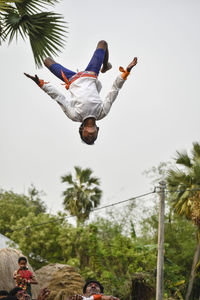 Low angle view of people jumping against sky