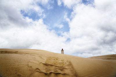 Low angel view of lighthouse over sand dunes against sky