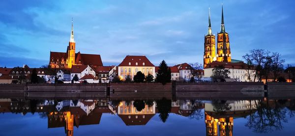 Reflection of illuminated buildings in lake against sky