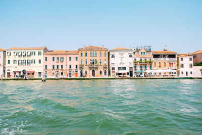 View of buildings by sea against clear sky