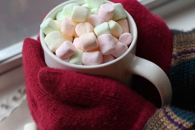 Cropped hand holding hot chocolate by window