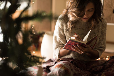 Young woman looking away while sitting on book