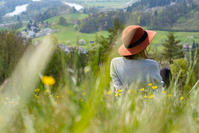 Rear view of woman with hat sitting on field