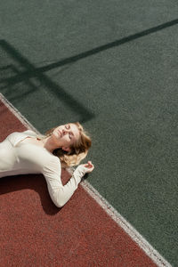 High angle view of young woman lying on soccer field