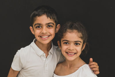 Portrait of smiling boy against black background