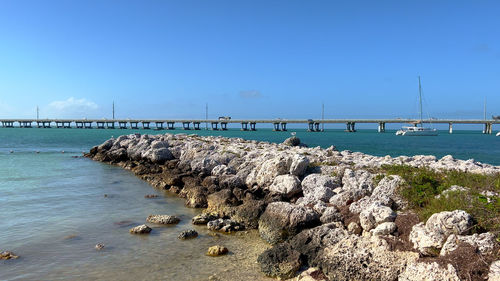 Pier over sea against clear blue sky