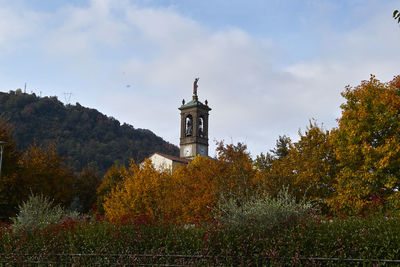 Tower amidst trees and buildings against sky