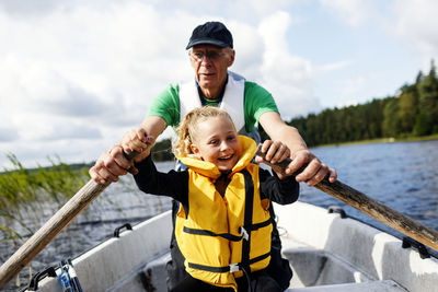 Father and son in boat against sky