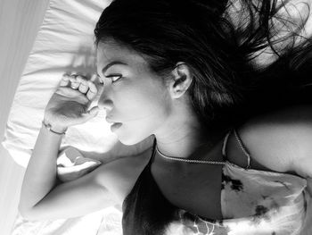 High angle view of young woman looking away while lying on bed at home