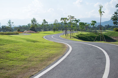 Road amidst green landscape against sky