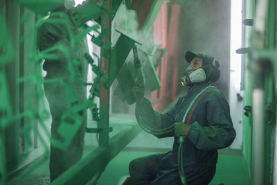 Painters spraying steel components in spray booth of a factory