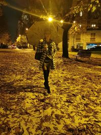 Full length of woman walking on illuminated street at night