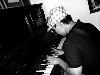 Side view of man playing piano at home