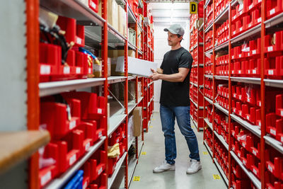 Warehouse worker removing box from rack standing in factory