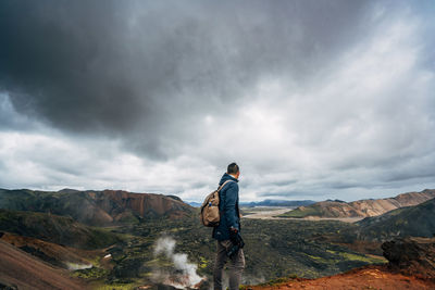 Hiker looking at landscape against cloudy sky