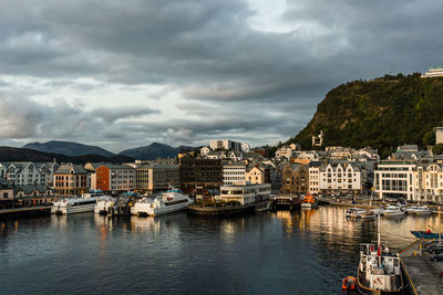 Sailboats moored at harbor by buildings in city against sky