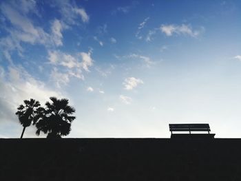 Low angle view of silhouette palm trees and building against sky