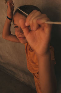 High angle portrait of girl holding rope while standing against wall