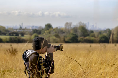 Rear view of man photographing on field