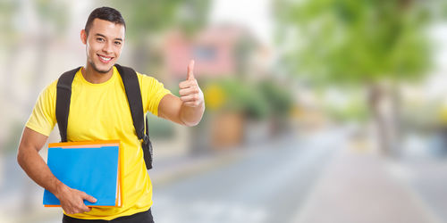 Portrait of young man holding yellow while standing outdoors