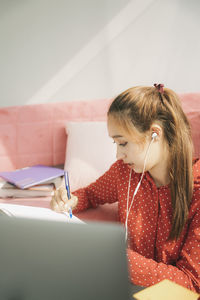 Teenage girl writing in book at home
