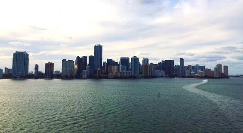 Sea by cityscape against sky