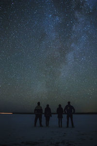 Silhouette friends standing against star field at night