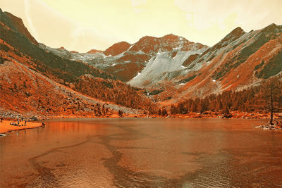 Scenic view of lake by mountains against sky