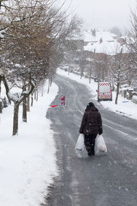 Rear view of man walking on snow covered field