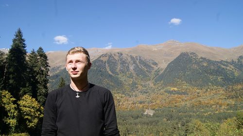 Man looking away while standing against mountain