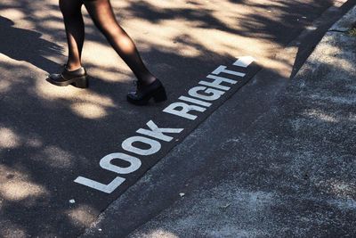 Low section of woman walking by markings on road