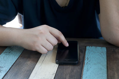 Midsection of woman using mobile on table