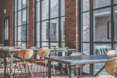 Empty chairs and table against window