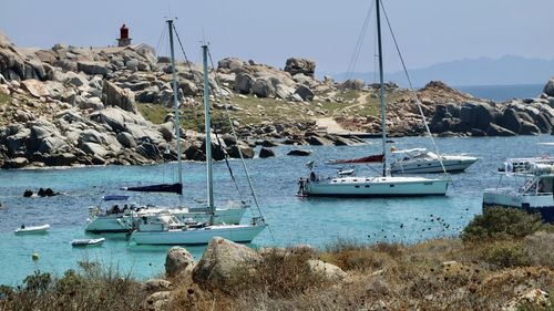 Sailboats moored in sea against sky