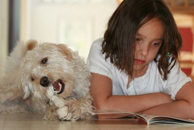 Cute girl with dog sitting at home