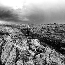 Rear view of man on rock against sky