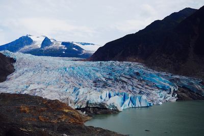 Scenic view of icebergs and mountains against sky