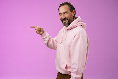 Midsection of man standing against pink background