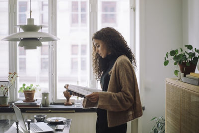 Side view of woman using mobile phone at home